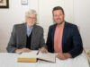 Würdigung für Nieder-Olmer Chronisten Peter Weisrock trägt sich ins Goldene Buch der Stadt Nieder-Olm ein. Damit würdigt die Kommune die Verdienste des Chronisten zur Stadtgeschichte - hier zusammen mit Stadtbürgermeister Dirk Hasenfuss. Foto: Annette Pospesch